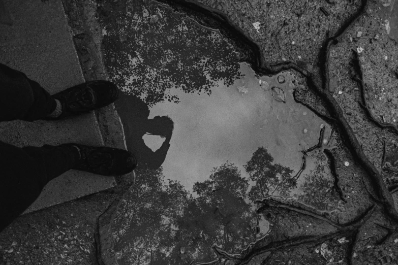 a person standing next to a puddle of water, a black and white photo, by Maria van Oosterwijk, in love selfie, broken heart, paved, australian tonalism escher