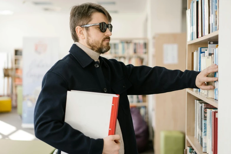 a man standing in front of a book shelf holding a folder, trending on reddit, implanted sunglasses, teacher, security agent, high quality photo