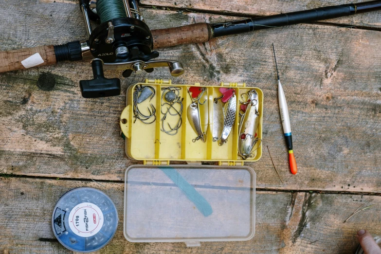 a box filled with fishing tools sitting on top of a wooden floor, by Tom Wänerstrand, trending on pexels, 1980s photo, piercing, ilustration, 33mm photo