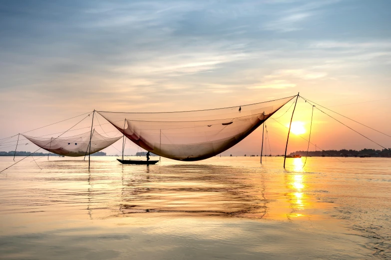 a group of fishing nets sitting on top of a body of water, inspired by Christo, pexels contest winner, vietnam, sunlit sky, silk tarps hanging, warm coloured