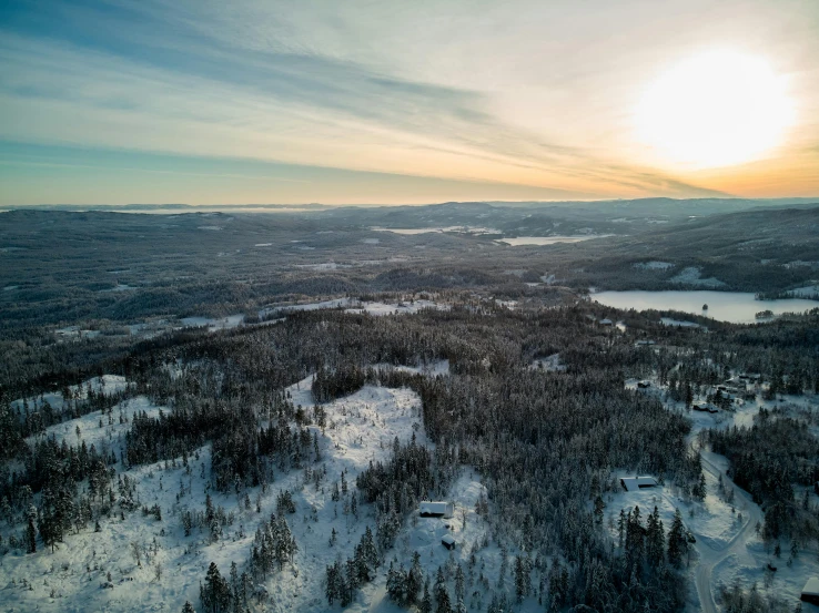 a person riding a snowboard on top of a snow covered slope, by Jaakko Mattila, pexels contest winner, hurufiyya, aerial view of an ancient land, taiga landscape, late morning, forest with lake