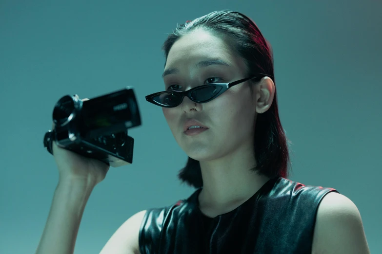 a woman holding a camera up to her face, an album cover, inspired by Zhu Da, unsplash, neo-dada, wearing space techwear, ar glasses, cinematic outfit photo, kiko mizuhara
