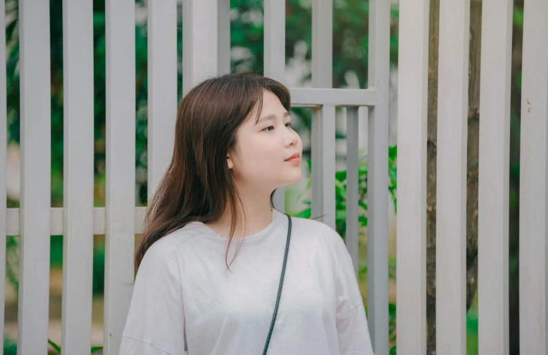 a woman standing in front of a white fence, inspired by Kim Jeong-hui, pexels contest winner, realism, young cute wan asian face, three quarter profile, student, round chin