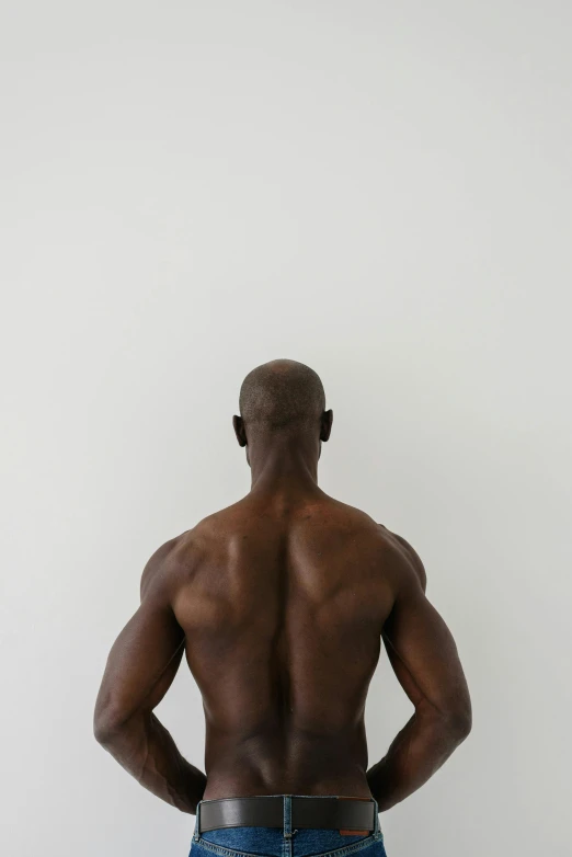 a man standing with his back to the camera, by Brian Alfred, lance reddick, defined muscles, in front of white back drop, photographed for reuters