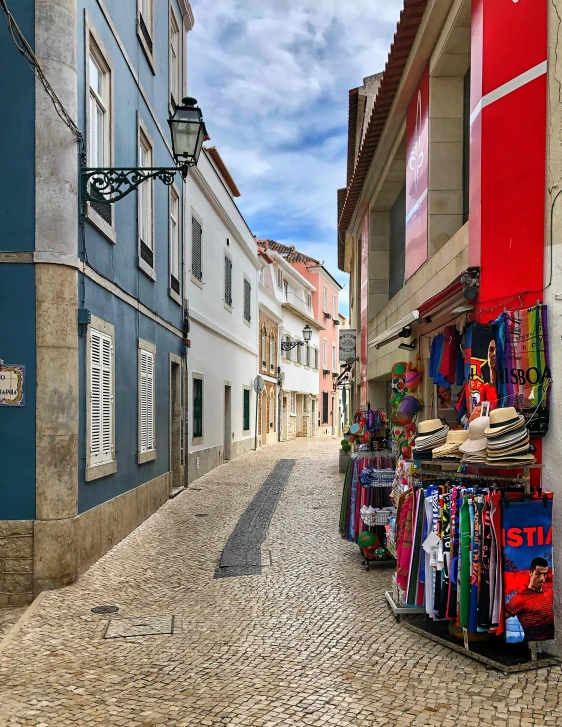 a narrow cobblestone street lined with shops, pexels contest winner, nazare (portugal), red and blue garments, square, album photo