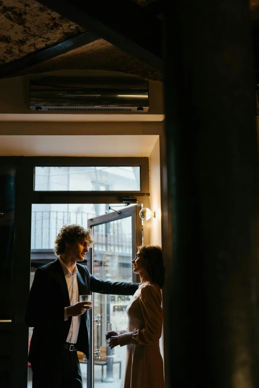 a man and a woman standing in front of a door, pexels contest winner, happening, inside a bar, window light, rooftop romantic, max dennison