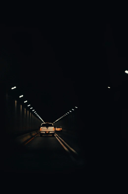 a car driving through a tunnel at night, a picture, unsplash, minimalism, analog photo, dramatic lighting - n 9, cars