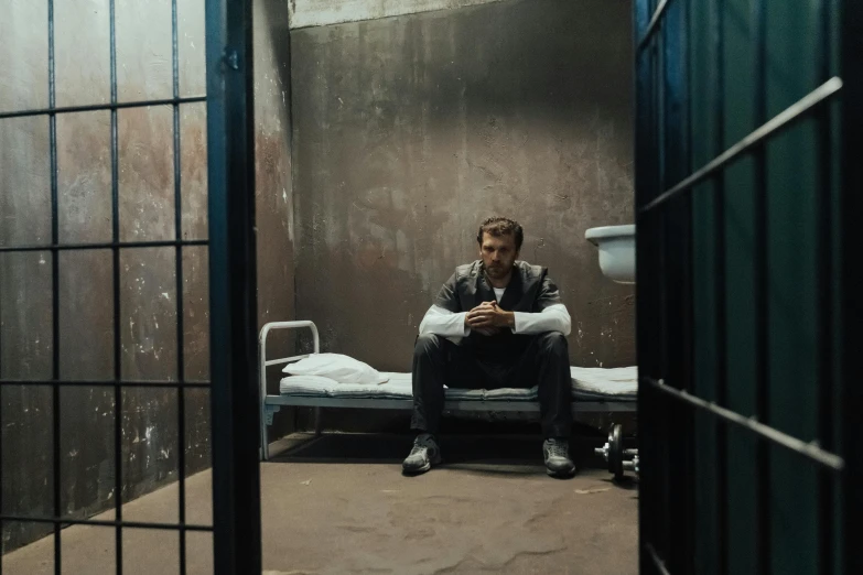 a man sitting on a bed in a jail cell, pexels contest winner, antony starr, lachlan bailey, **cinematic, orelsan