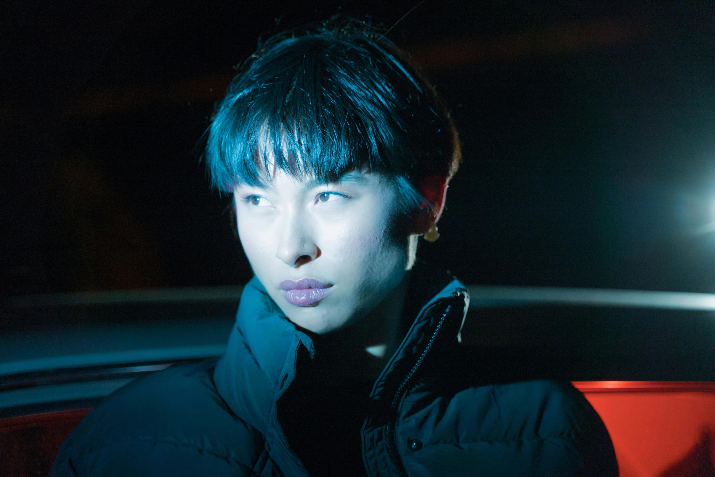 a man standing in front of a car at night, an album cover, inspired by Liam Wong, pexels, realism, short blue haired woman, actor, hito steyerl, close-up portrait film still