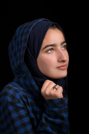 a woman wearing a blue and black scarf, an album cover, by Maryam Hashemi, unsplash contest winner, hyperrealism, portrait of teenage girl, standing with a black background, thoughtful pose, photographed for reuters