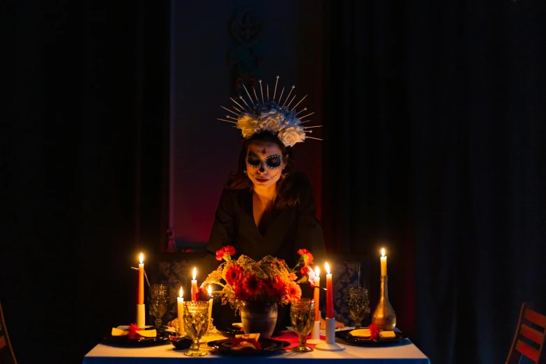 a woman sitting at a table with candles in front of her, by Liza Donnelly, pexels contest winner, vanitas, voodoo hat, with a spine crown, slide show, dinner is served