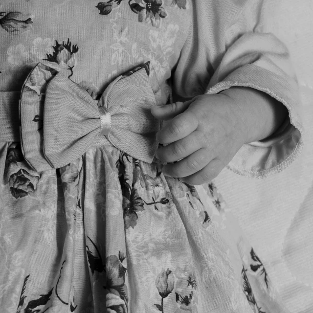 a black and white photo of a little girl in a dress, by Emma Andijewska, pexels contest winner, process art, hands pressed together in bow, georgian dress amazing fabric, detail shots, 🌸 🌼 💮