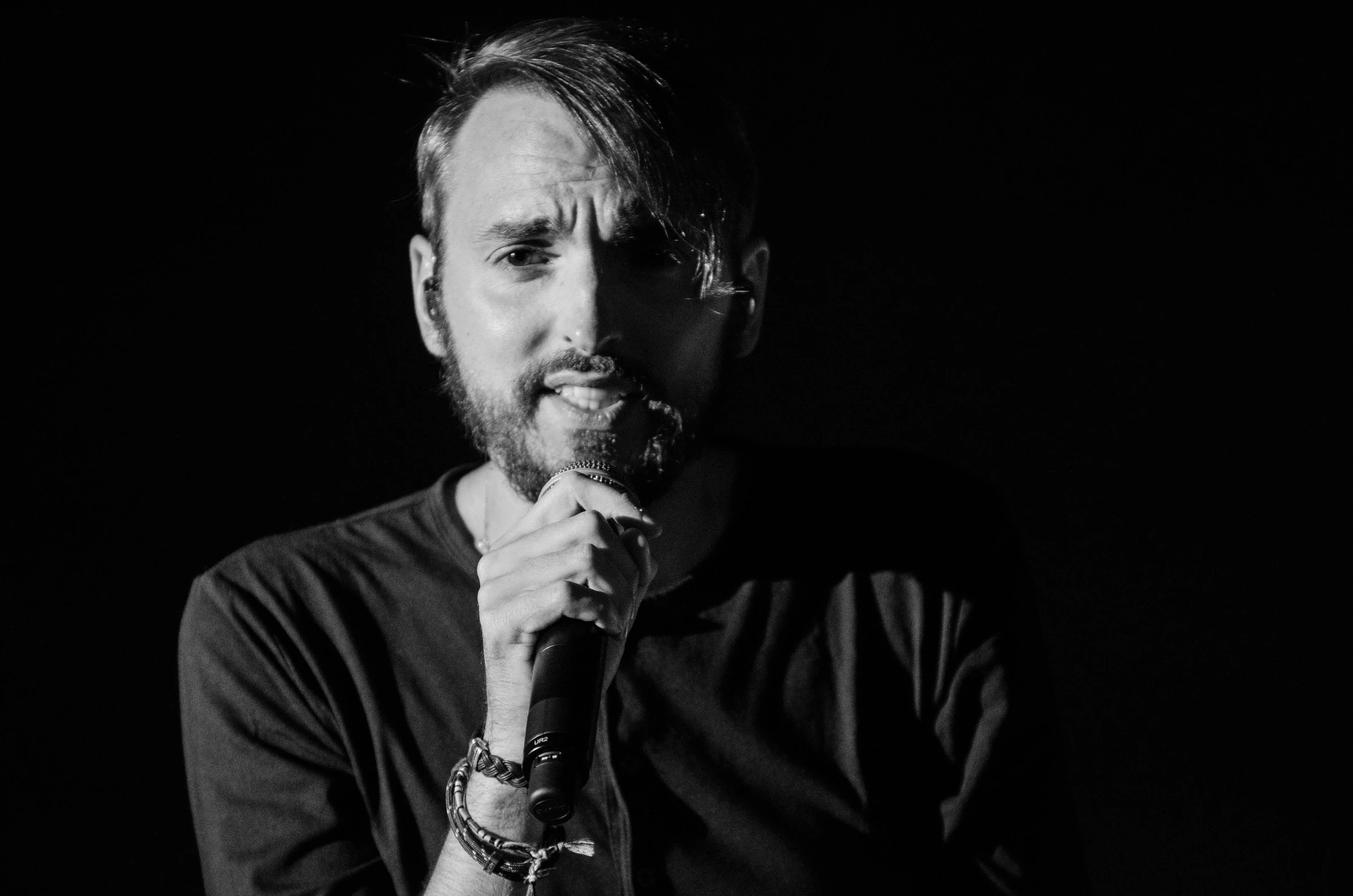 a black and white photo of a man holding a microphone, a black and white photo, by Andrei Kolkoutine, with a beard and a black shirt, mr beast, 15081959 21121991 01012000 4k, asmongold