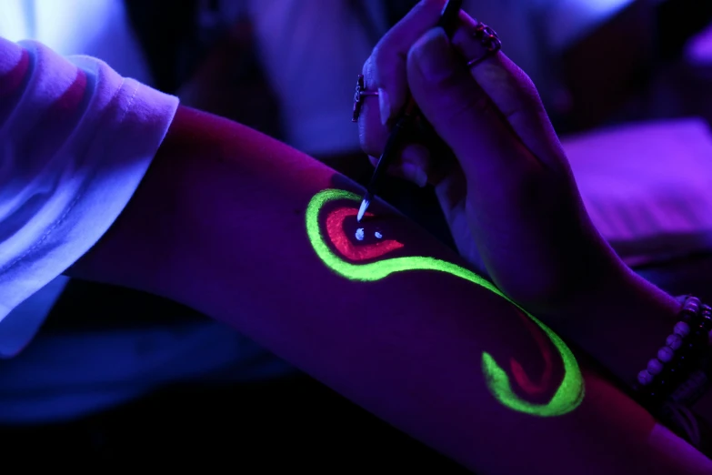 a close up of a person holding a cell phone, an airbrush painting, trending on pexels, interactive art, glow sticks, luminous body, lime and violet, inking on skin