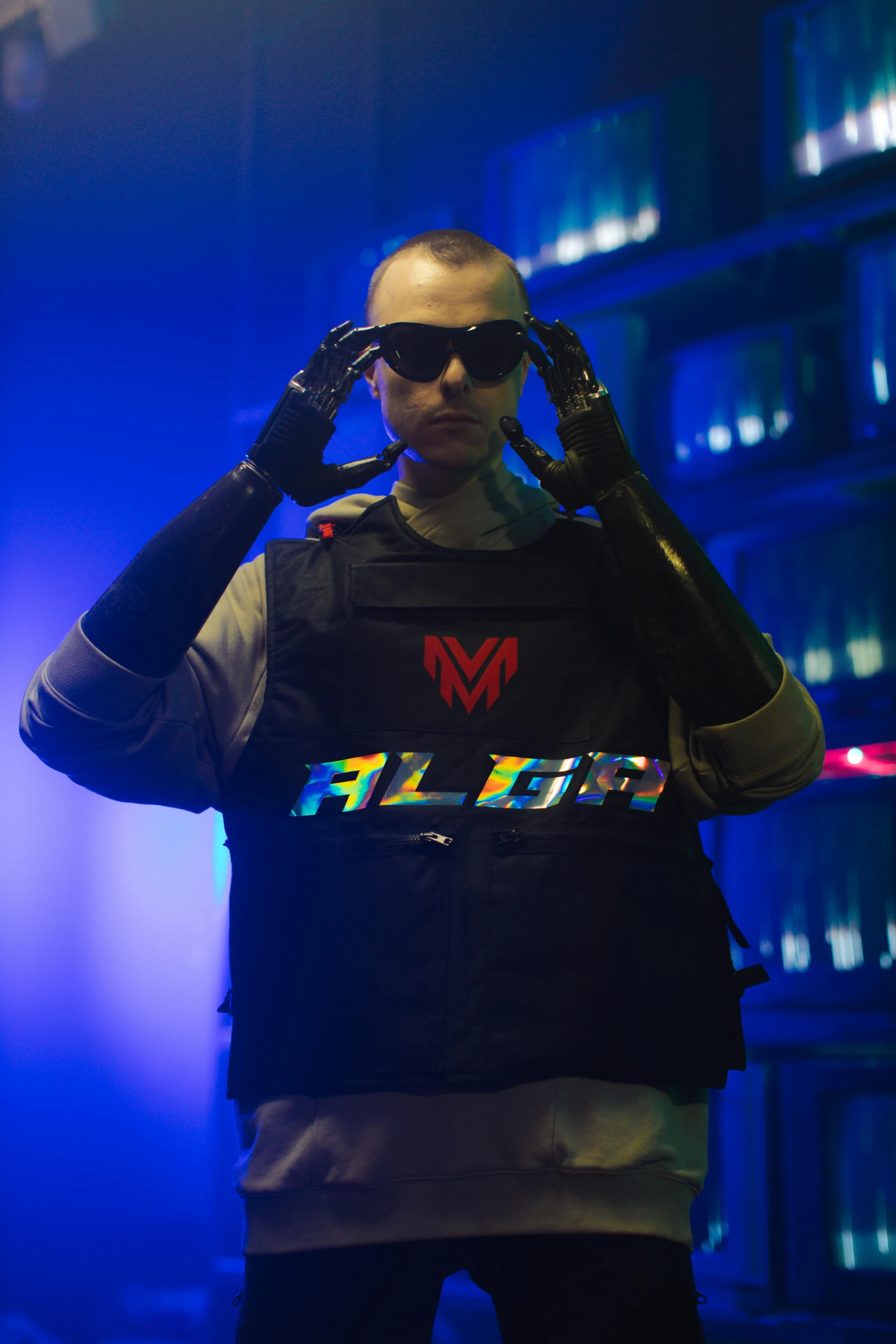 a man standing in front of a blue light, an album cover, inspired by Adam Marczyński, featured on reddit, altermodern, wearing techwear and armor, cyberpunk sunglasses, model is wearing techtical vest, mr clean