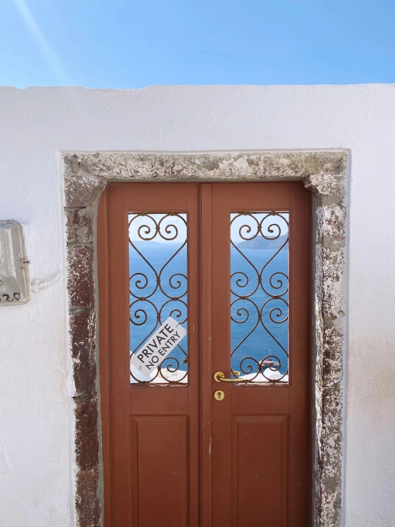 a couple of brown doors sitting on top of a white building, by Alexis Grimou, low quality photo, greek elements, sign, trending photo