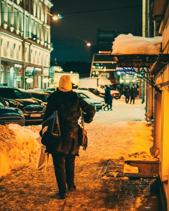 a woman walking down a snowy street at night, pexels contest winner, non-binary, russian city, brightly lit, with his back turned