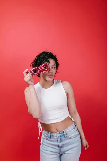 a woman holding a doughnut in front of her face, an album cover, pexels contest winner, minimalism, red neon roses, red tank-top, dark short curly hair smiling, shot with sony alpha 1 camera