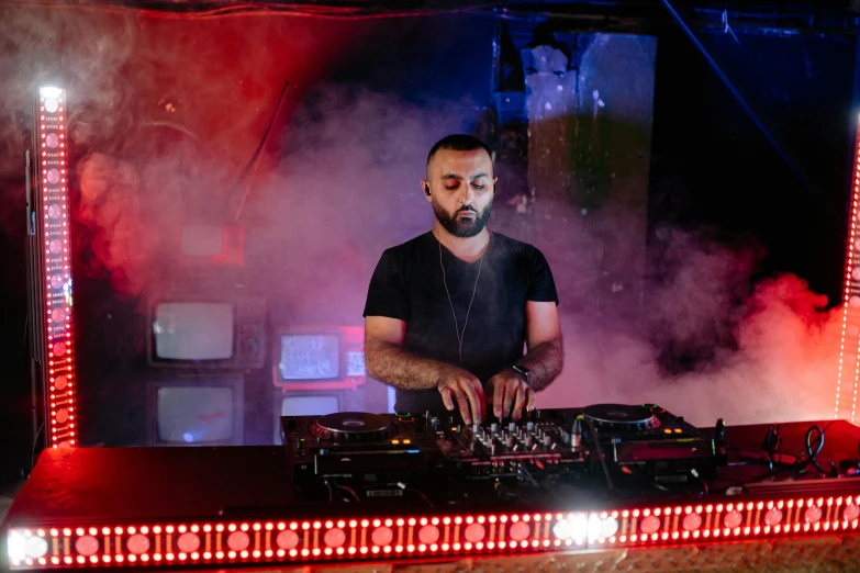 a man that is standing in front of some lights, les nabis, dj set, with red haze, shabab alizadeh, mixing drinks