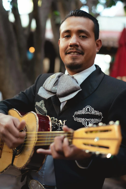 a man that is holding a guitar in his hand, inspired by Germán Londoño, happening, mexico city, slightly smiling, ornately dressed, al fresco