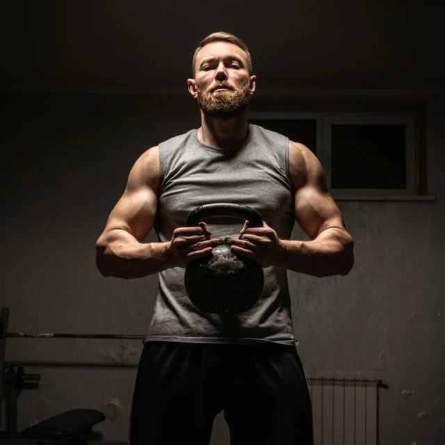 a man holding a kettlebell in a dark room, by Adam Marczyński, bearded and built, strong chest, profile image