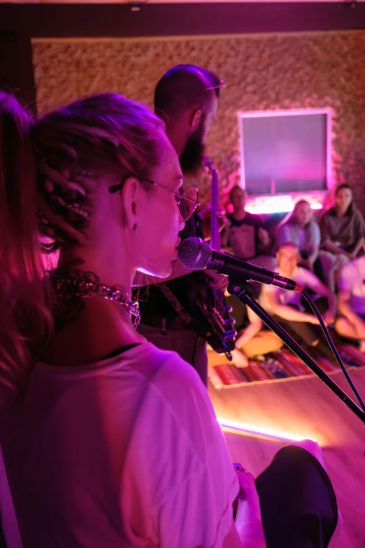 a group of people sitting in front of a microphone, soft calm warm neon atmosphere, profile image, blonde, performing