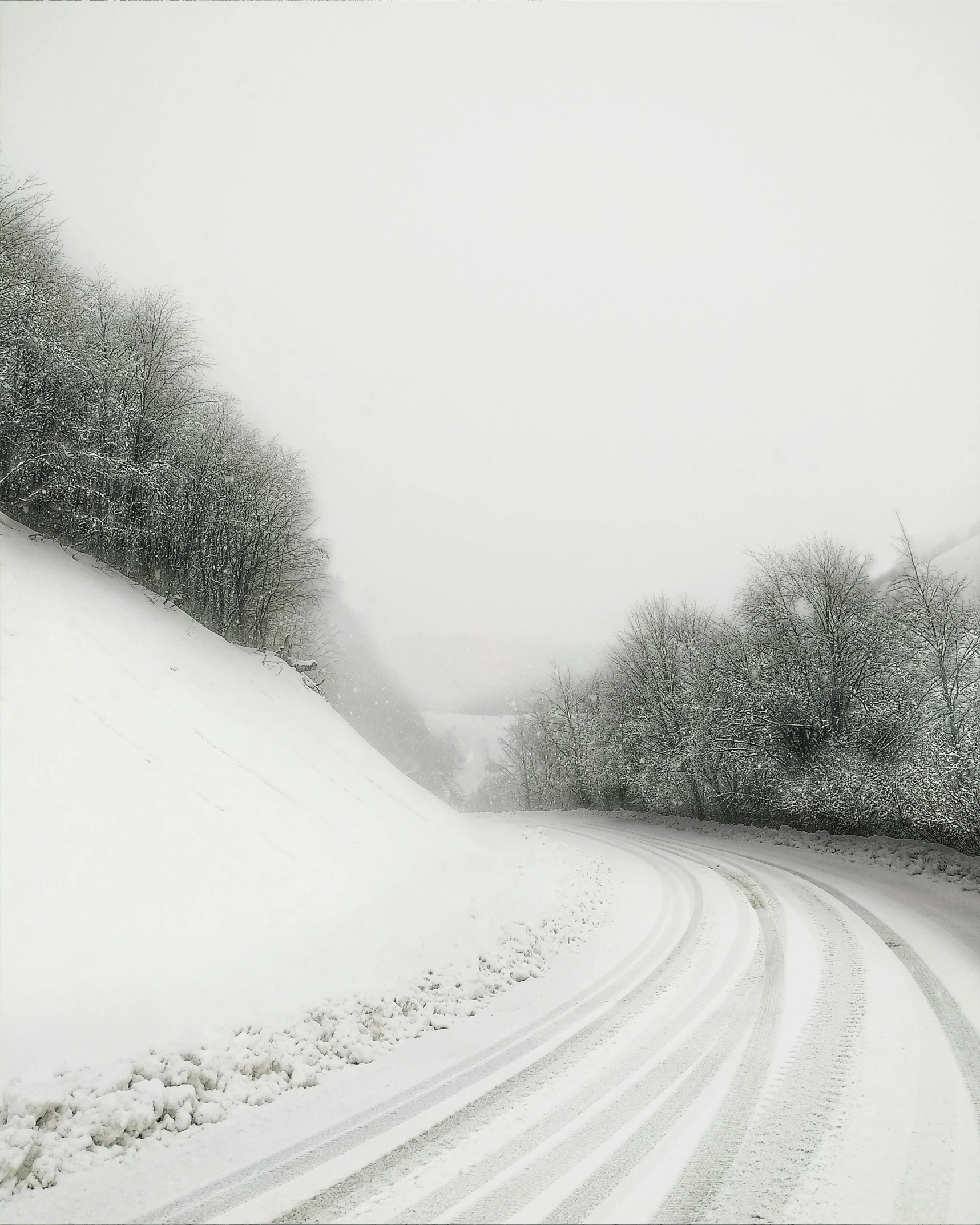 a black and white photo of a snowy road, an album cover, by Alison Geissler, pexels contest winner, a painting of white silver, road between hills, color photo, monia merlo