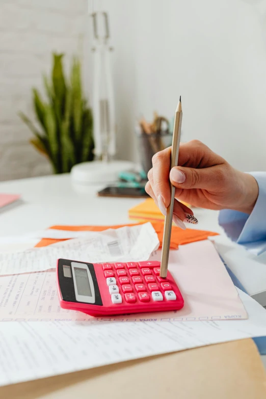 a person sitting at a desk with a calculator and a pen, pink and red color scheme, zoomed in, at checkout, thumbnail