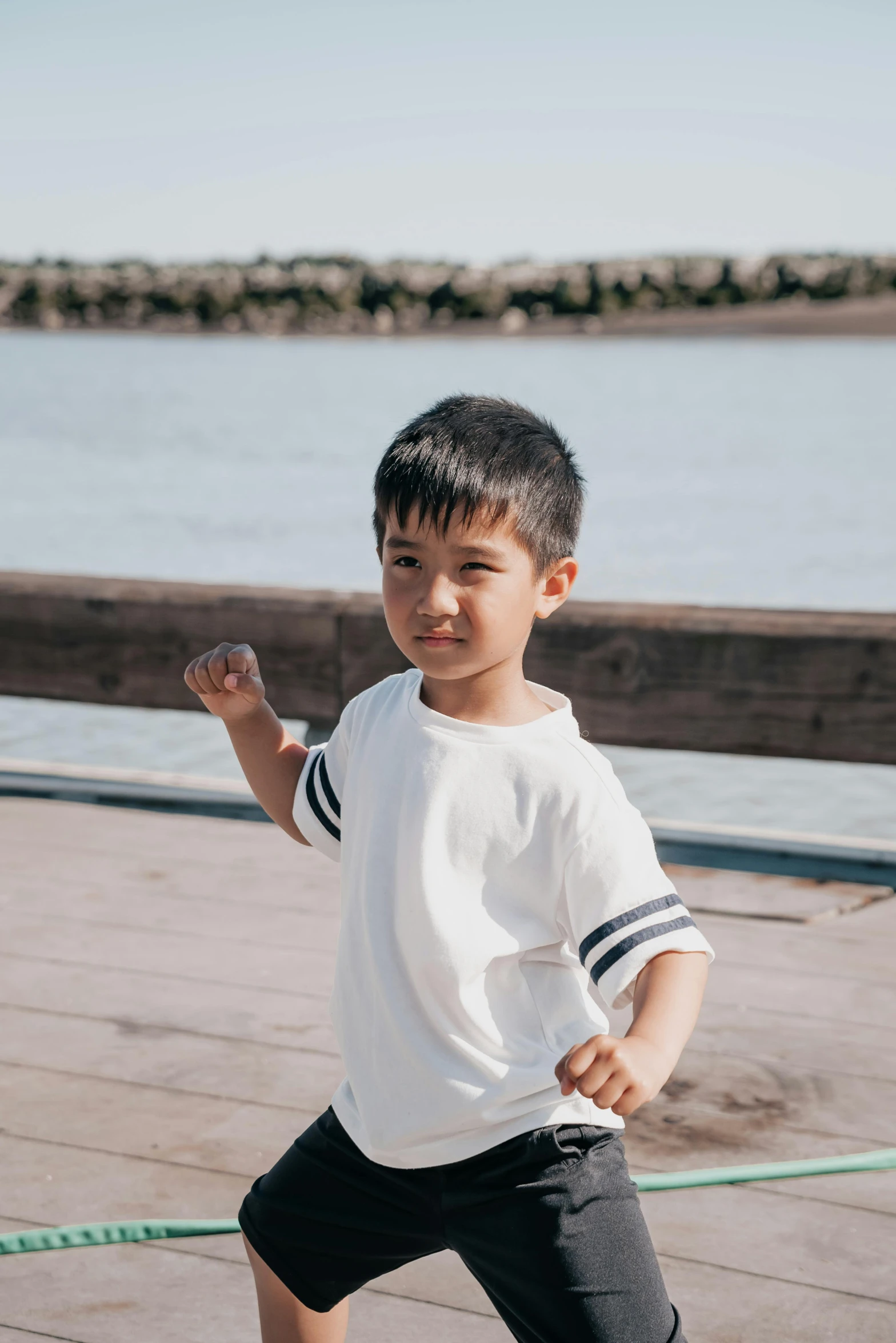 a little boy that is standing on a skateboard, inspired by Liang Kai, pexels contest winner, happening, wearing a tee shirt and combats, at the waterside, showing strong muscles, white sleeves