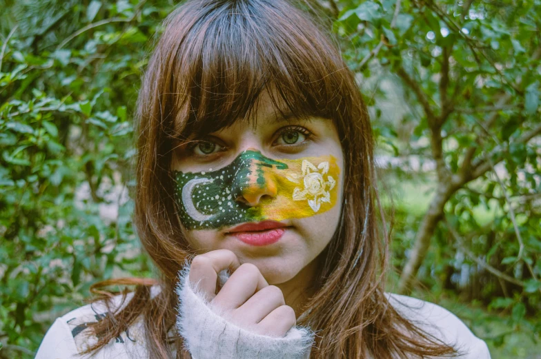 a close up of a person with a painted face, an album cover, by Julia Pishtar, pexels contest winner, hurufiyya, brazilian flag, cottage hippie naturalist, islamic, young southern woman