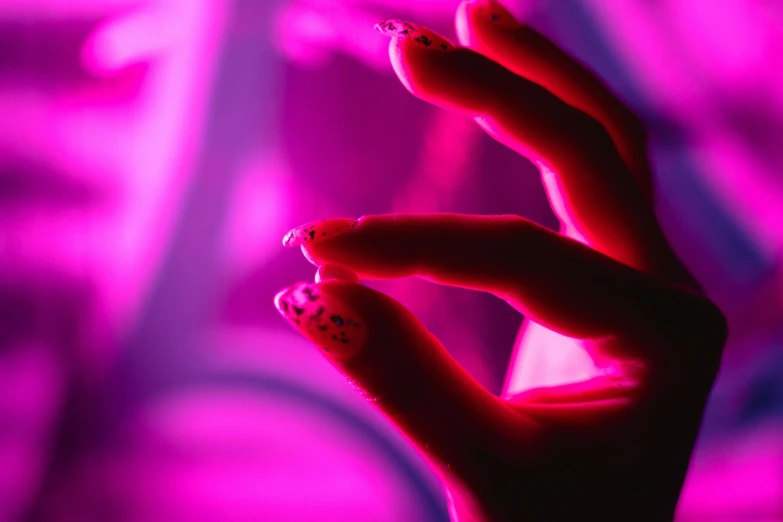 a close up of a person's hand with nail polish, an album cover, inspired by Elsa Bleda, pexels, aestheticism, bright pink purple lights, psychedelic photoluminescent, glowing people, infrared