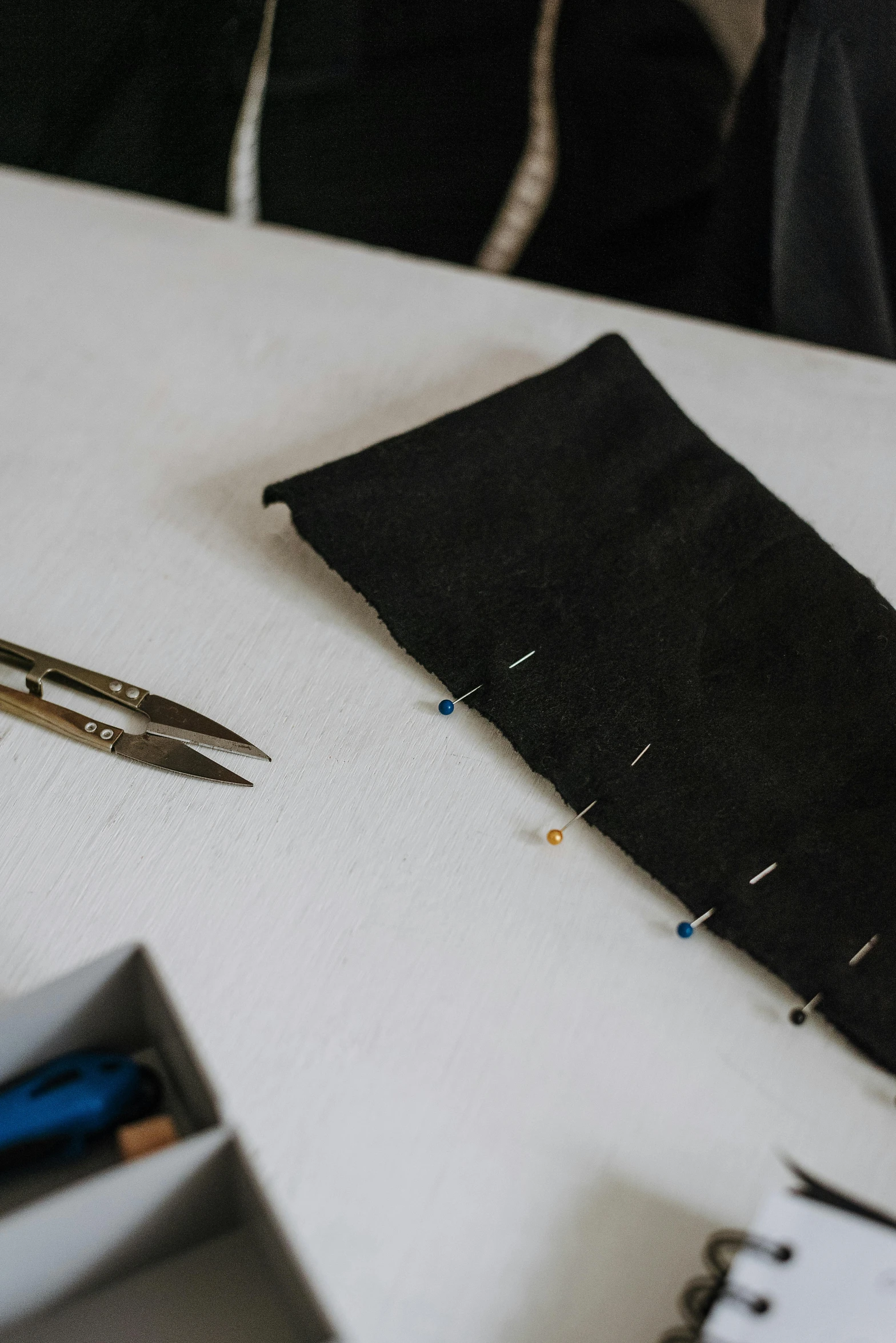 a pair of scissors sitting on top of a table, dark garments, black and blue scheme, rivets, hands on counter