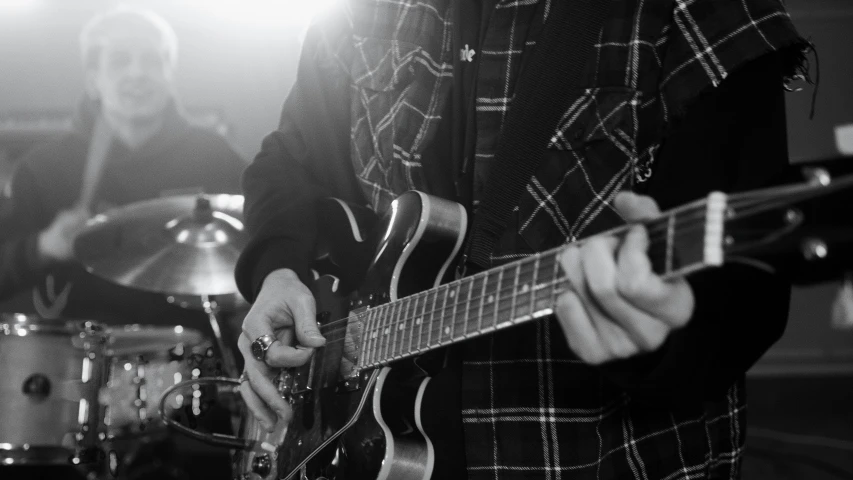 a black and white photo of a man playing a guitar, a black and white photo, by Neil Blevins, pexels, 15081959 21121991 01012000 4k, band playing, shining lights, holding a silver electric guitar