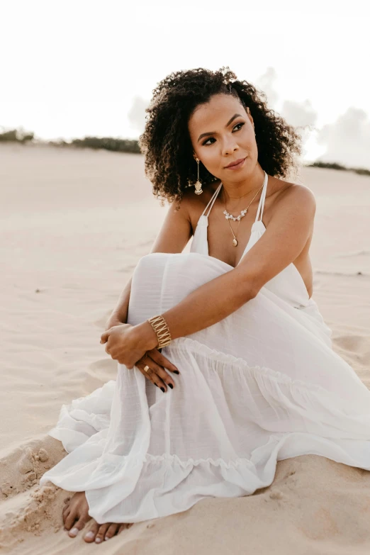 a woman sitting on top of a sandy beach, tessa thompson inspired, goddess jewelry, bright white, dune style