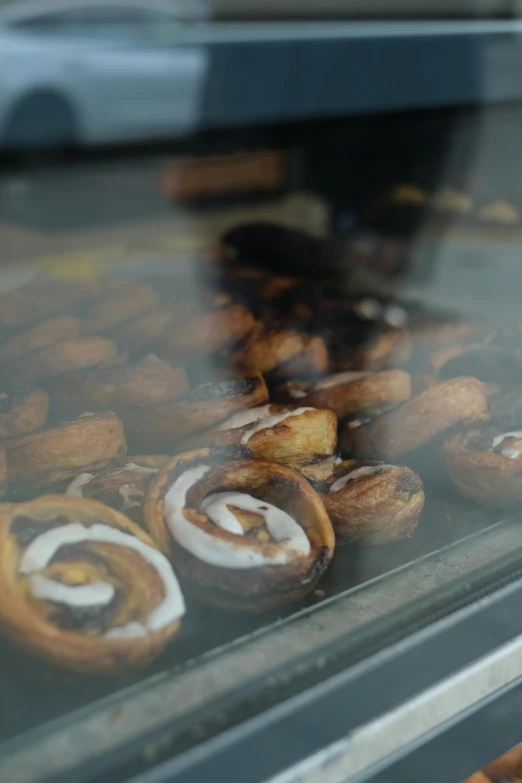 a display case filled with lots of pastries, a picture, in the shape of a cinnamon roll, smokey, thumbnail, candid shot