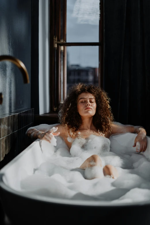 a woman taking a bubble bath in a bathtub, a portrait, inspired by Elsa Bleda, trending on pexels, renaissance, curly brown hair, city morning, girl clouds, sexy :8