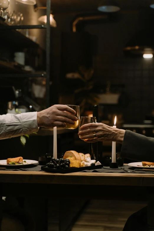 a couple of people that are sitting at a table, a still life, by Jesper Knudsen, pexels contest winner, renaissance, candlelit restaurant table, cheers, gray men, sleek hands