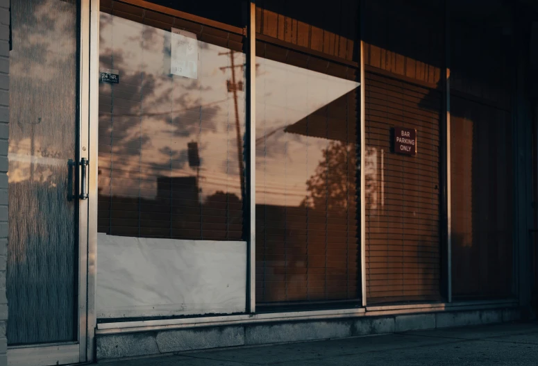 a red fire hydrant sitting in front of a building, an album cover, unsplash, hyperrealism, the sun reflecting on a window, convenience store, todd hido, bars on the windows