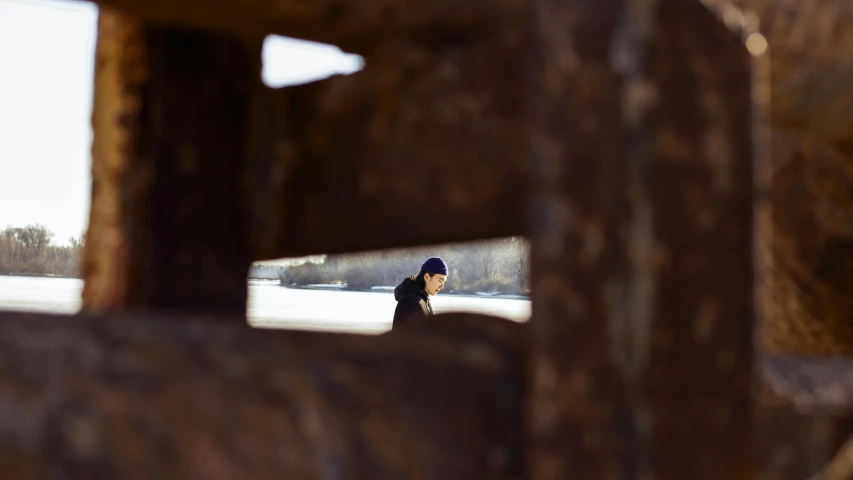 a man riding a skateboard down a snow covered slope, inspired by Louis Stettner, unsplash, conceptual art, looking through a window frame, old lumber mill remains, detailed unblurred face, stood in a cell