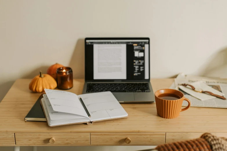 a laptop computer sitting on top of a wooden desk, trending on pexels, halloween, lined paper, sitting on a mocha-colored table, high quality photo