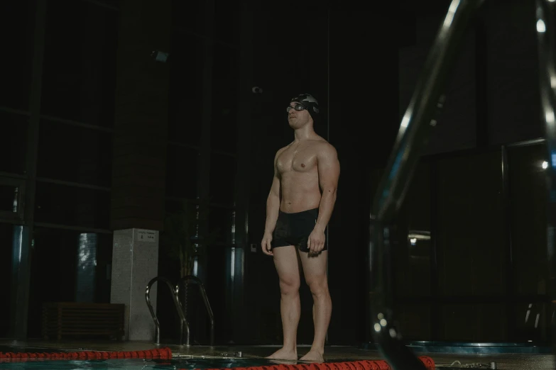 a man standing on the edge of a swimming pool, black undersuit, 8k 28mm cinematic photo, in a gym, full body 8k