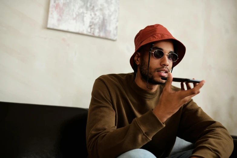 a man sitting on a couch smoking a cigarette, inspired by Barthélemy Menn, trending on pexels, red cap, brown skinned, shades, professional modeling