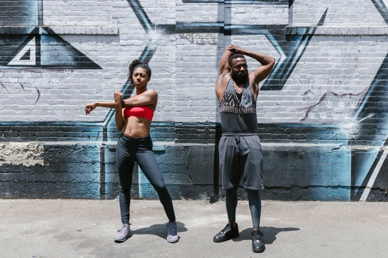 a couple of people that are standing in front of a wall, pexels contest winner, black arts movement, wearing fitness gear, choreographed, bowater charlie and brom gerald, in 2 0 1 8