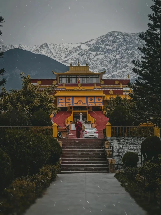 a yellow and red building with stairs leading up to it, inspired by Steve McCurry, pexels contest winner, cloisonnism, snow capped mountains, cybertronic hindu temple, moody setting, profile image