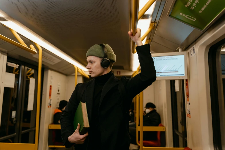 a woman holding a book on a subway train, pexels contest winner, graffiti, headphones on his head, wearing a turtleneck and jacket, meet the actor behind the scenes, finland