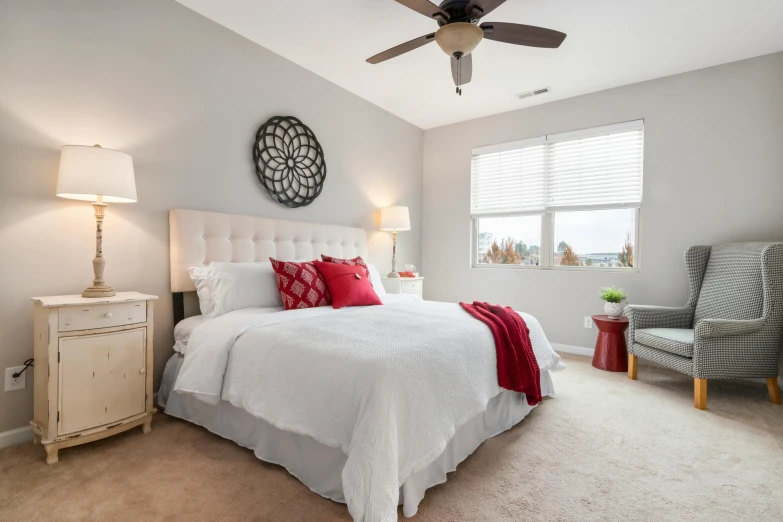 a white bed sitting in a bedroom next to a window, by Washington Allston, crimson accents, wide high angle view, one ceiling fan, set photo