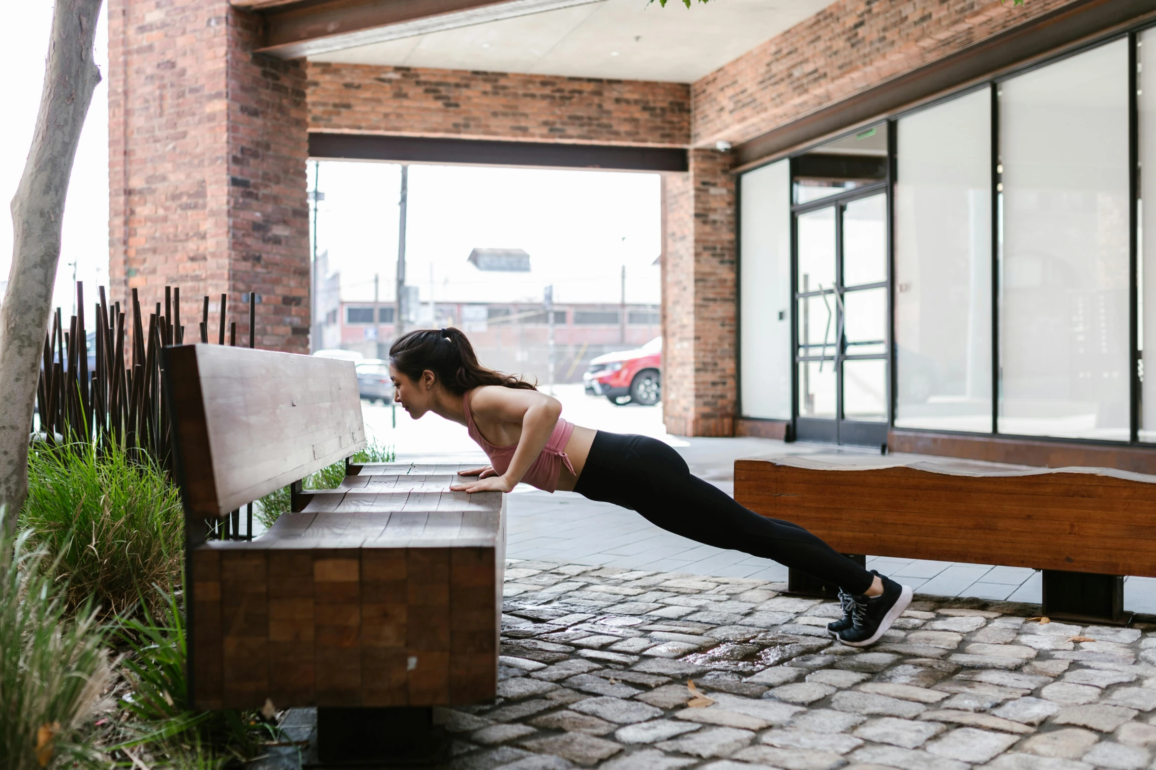 a woman doing push ups on a bench, by Jessie Algie, unsplash, square, dwell, in an urban setting, a wooden