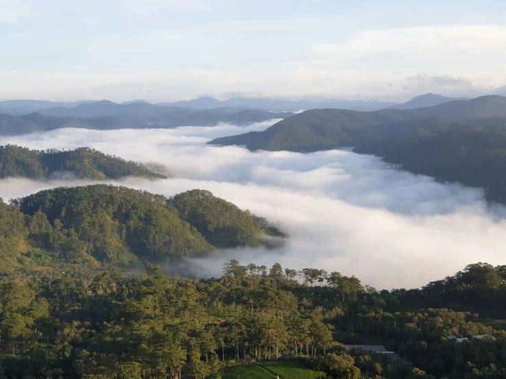 a view of a valley with mountains in the distance, by Jessie Algie, pexels contest winner, sumatraism, above low layered clouds, dezeen, tamborine, lush forest in valley below