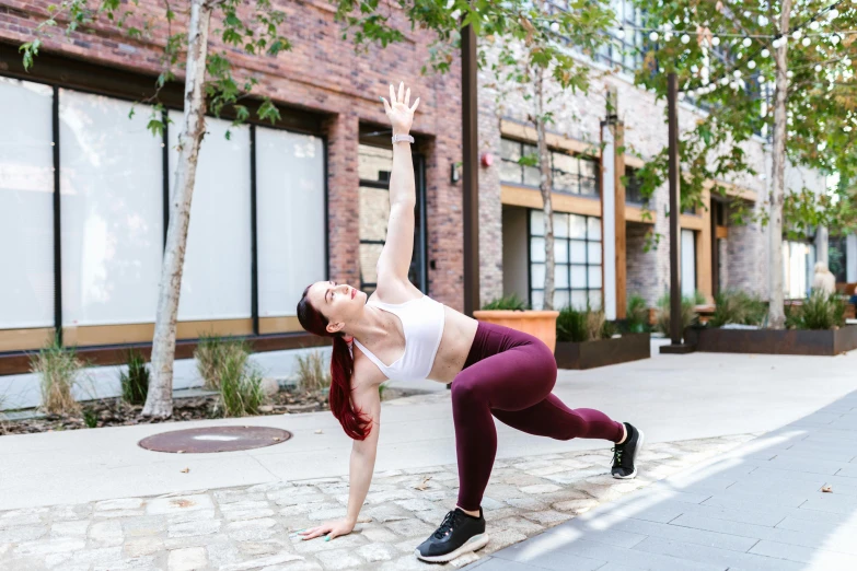 a woman doing a yoga pose on a sidewalk, by Carey Morris, pexels contest winner, arabesque, train with maroon, sydney hanson, curvy crossfit build, arms extended