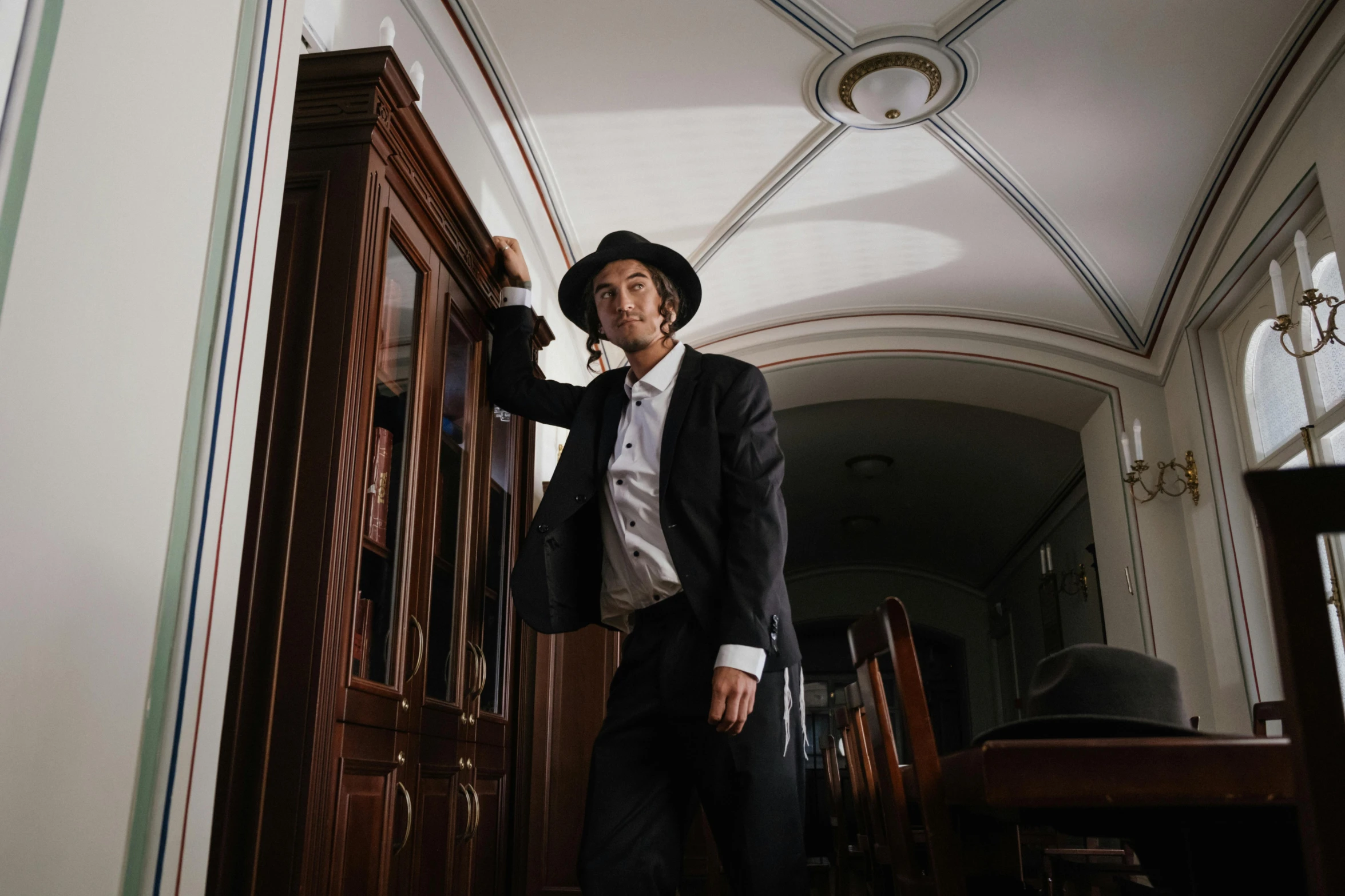 a man in a suit and hat talking on a cell phone, an album cover, by Emma Andijewska, unsplash, renaissance, leaning on door, asian man, posing elegantly, in the white house